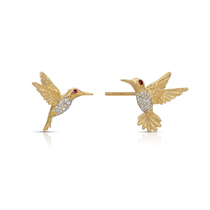 A pair of gold hummingbird stud earrings with diamond-encrusted bodies and small red gemstone eyes, shown on a clean white background.