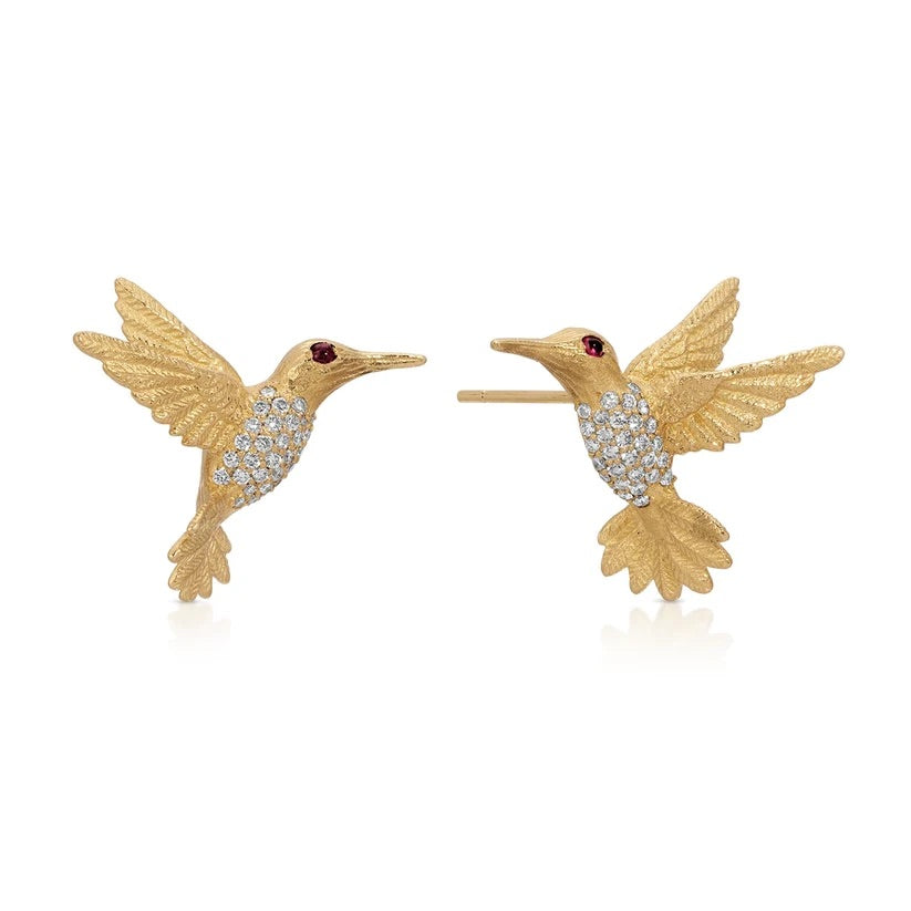A pair of gold hummingbird stud earrings with crystal-encrusted bodies and small red gemstone eyes, shown on a clean white background.
