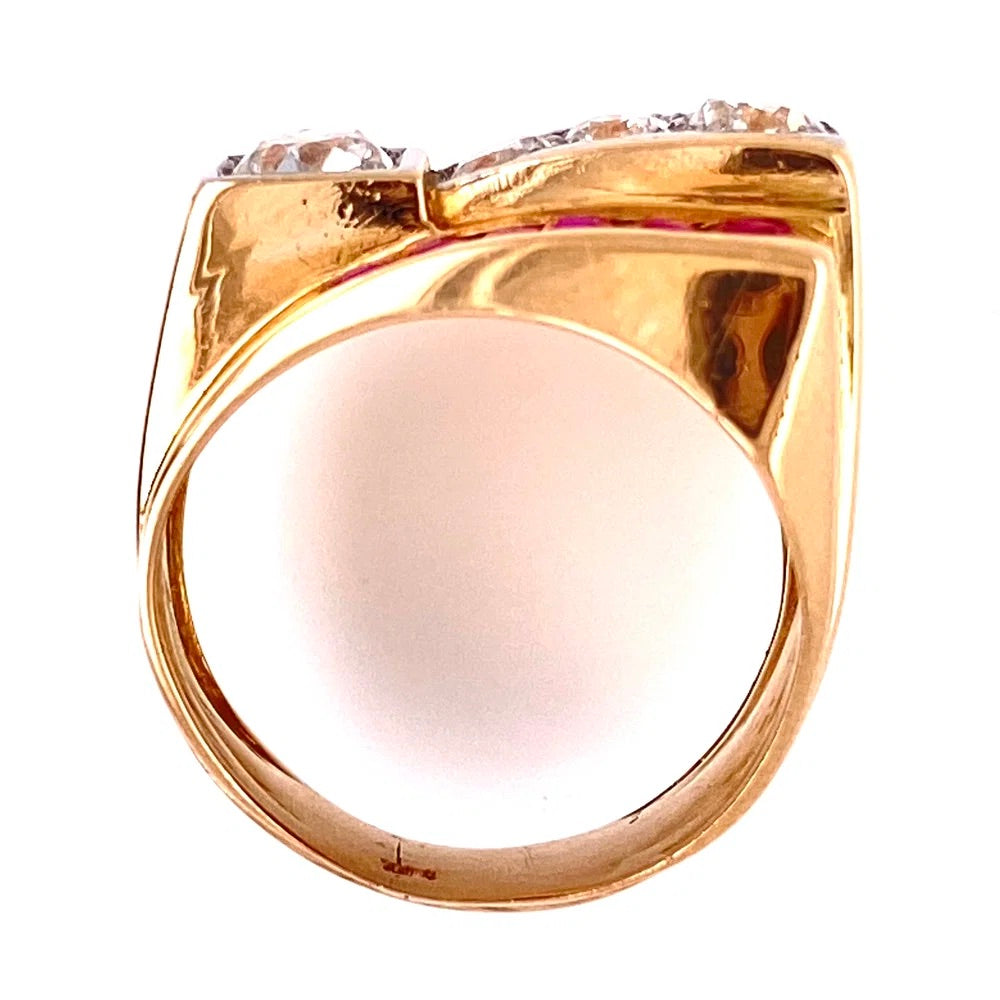 A close-up of a gold signet ring with a bow-like top setting small clear stones, shown on a plain white background.