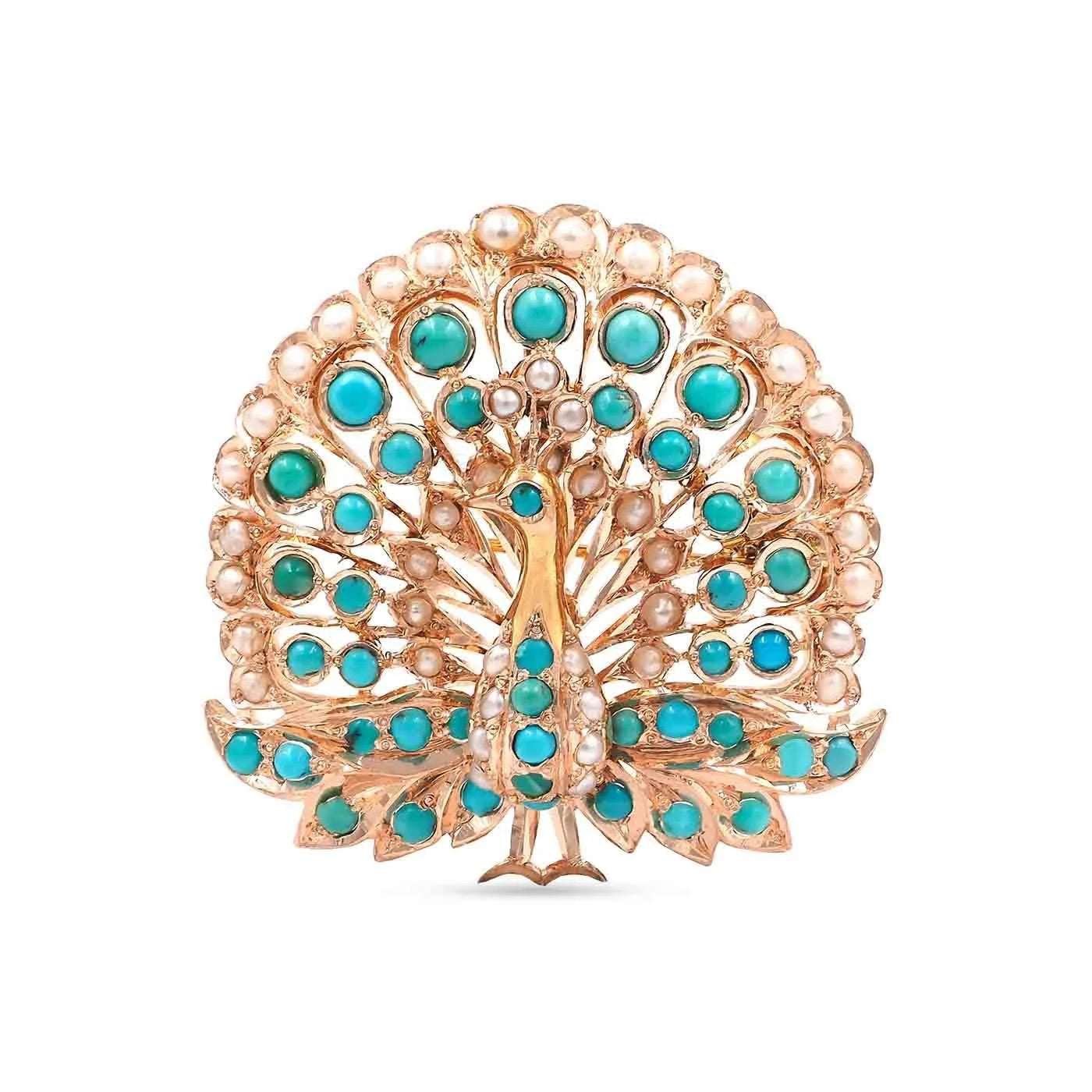 A peacock brooch featuring a gold-tone body and fan-shaped tail decorated with turquoise blue stones and small white pearls, set against a plain white background.