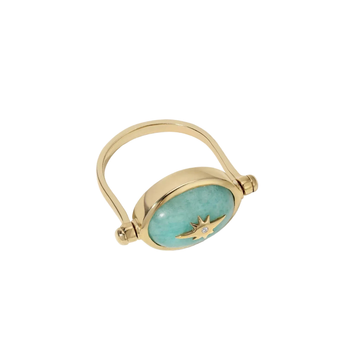 A gold ring featuring an oval light blue turquoise stone inlay with a gold starburst design and a small central clear gemstone, shown on a light cream background.