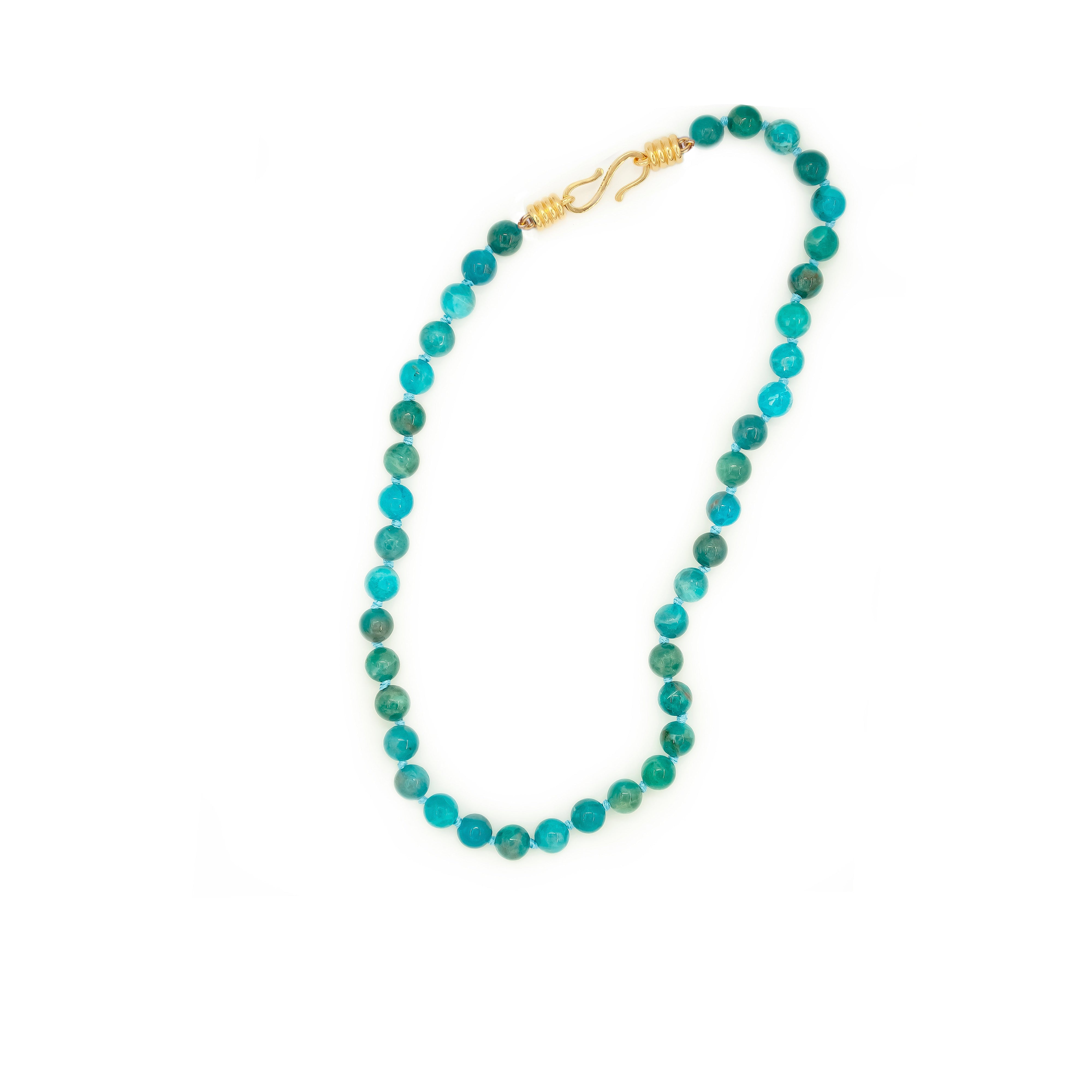 Necklace with turquoise beads and a gold clasp on a white background