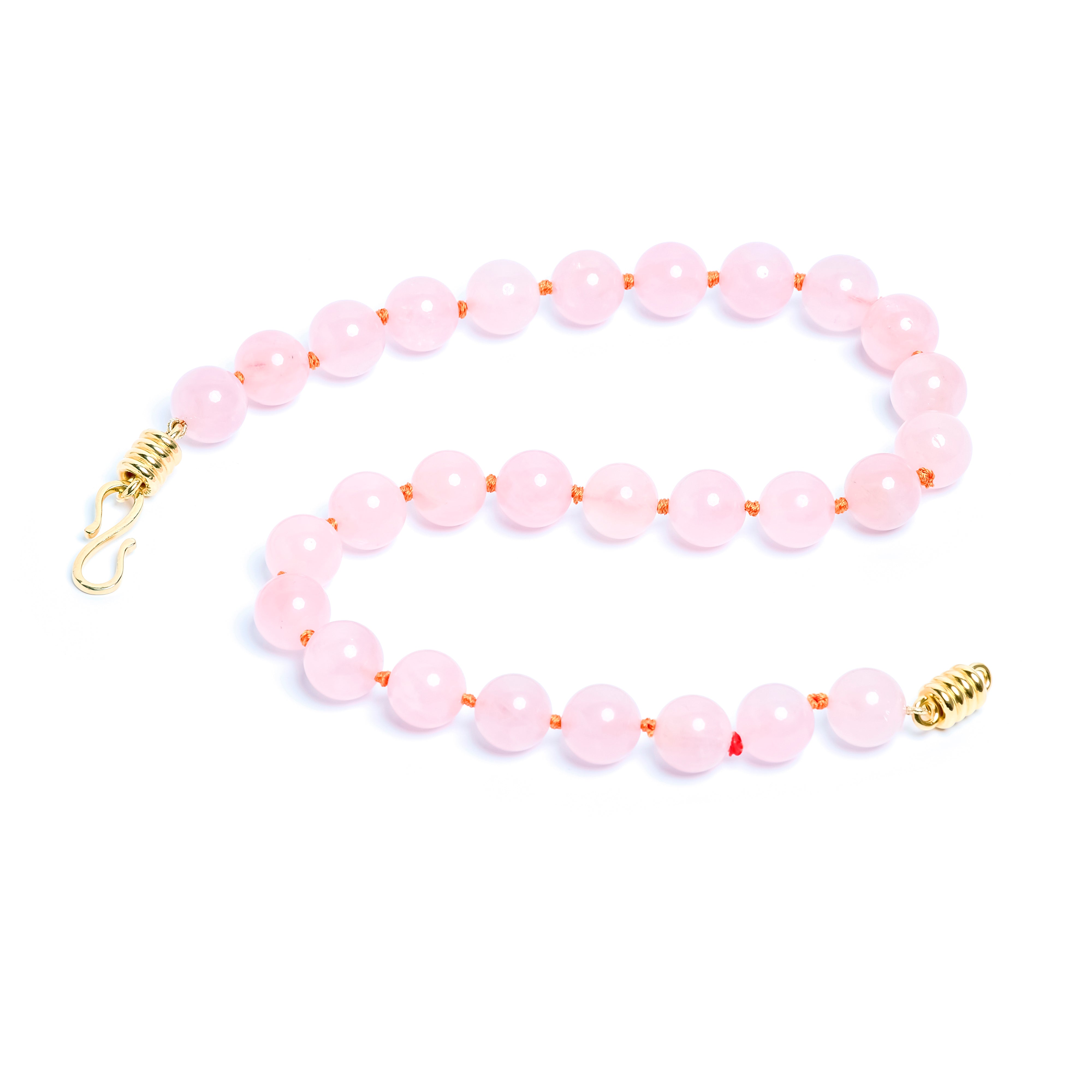Pink beaded necklace with gold clasp on a white background