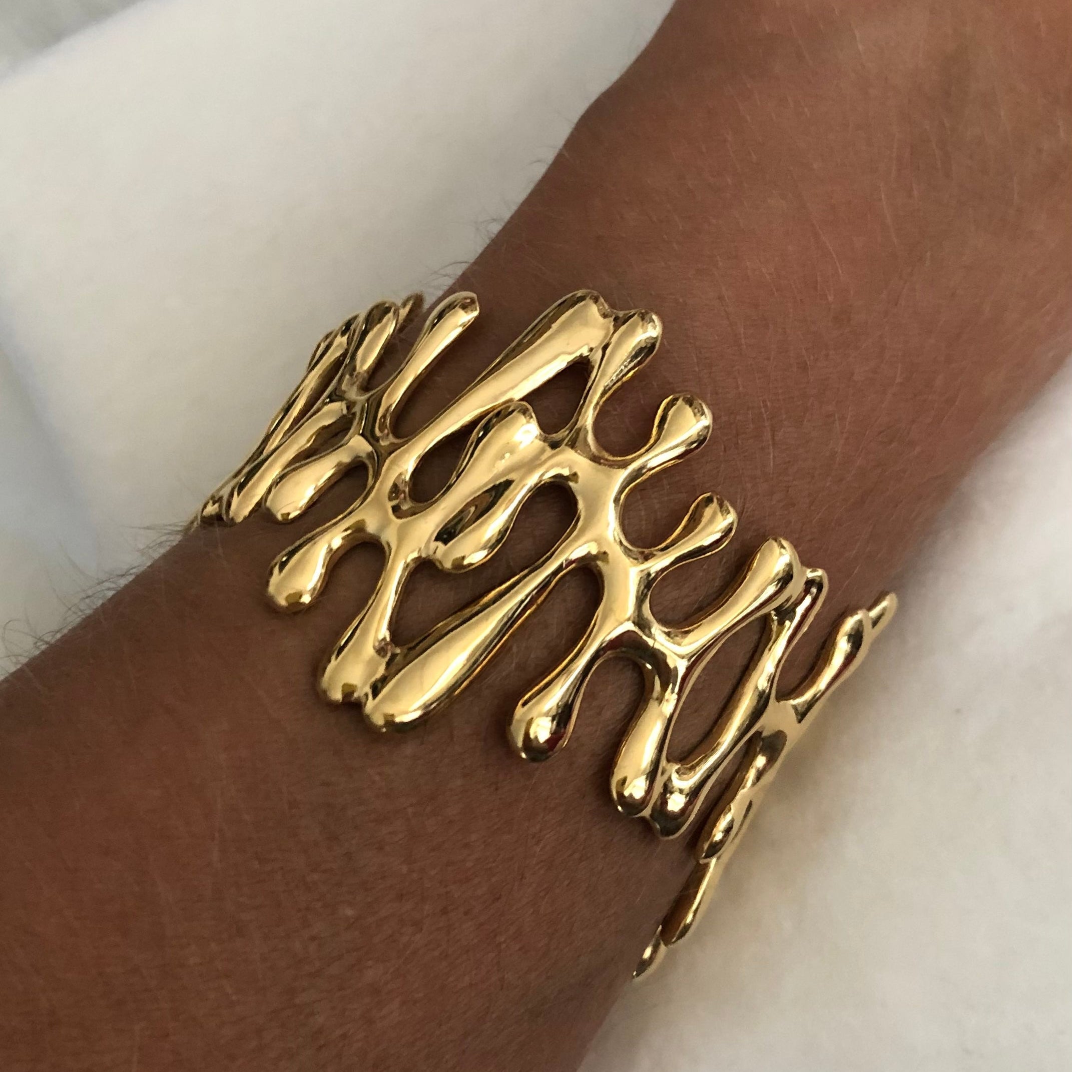 Gold bracelet on a wrist with a white background