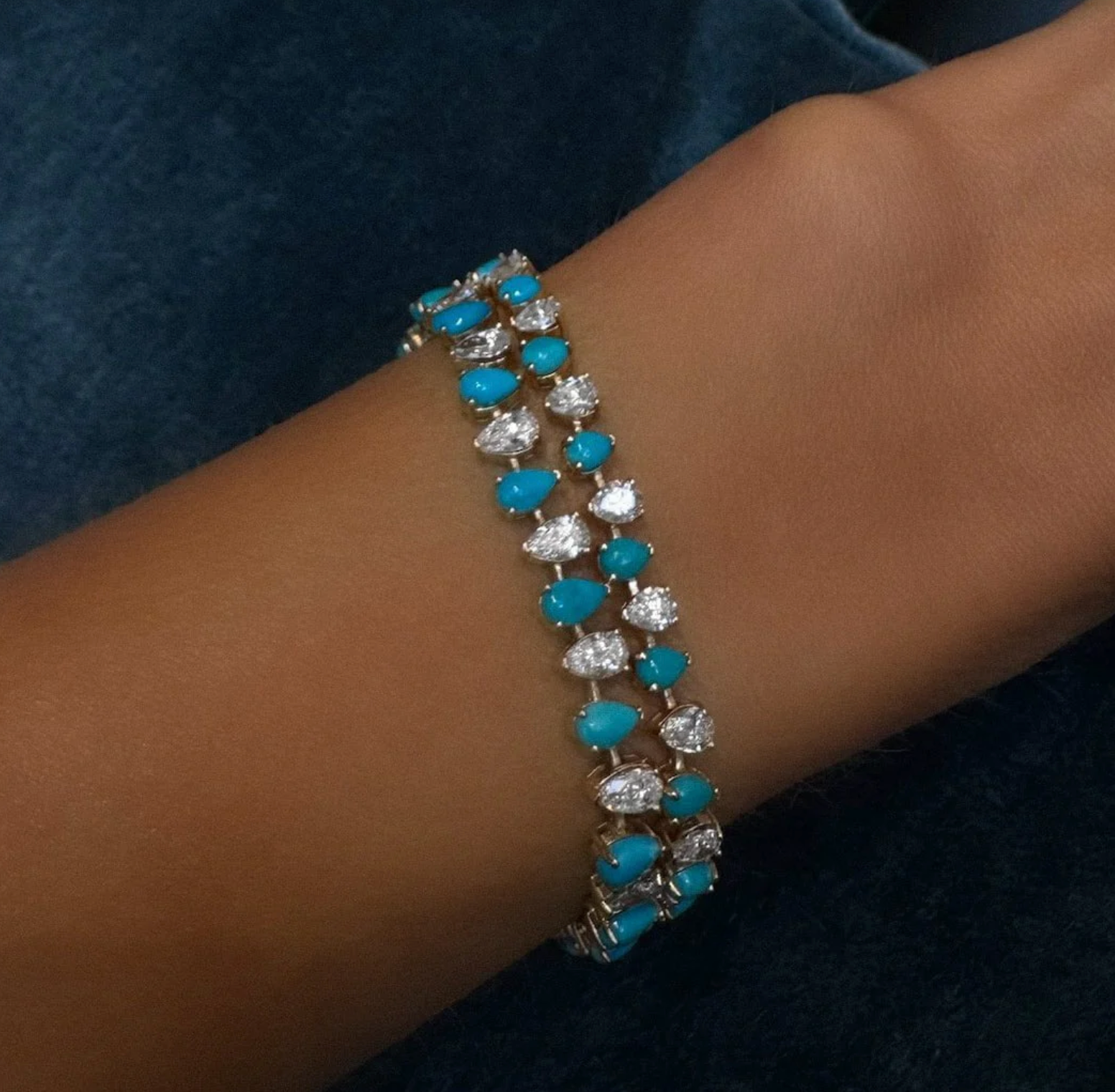 Turquoise and diamond bracelet on a wrist against a dark background