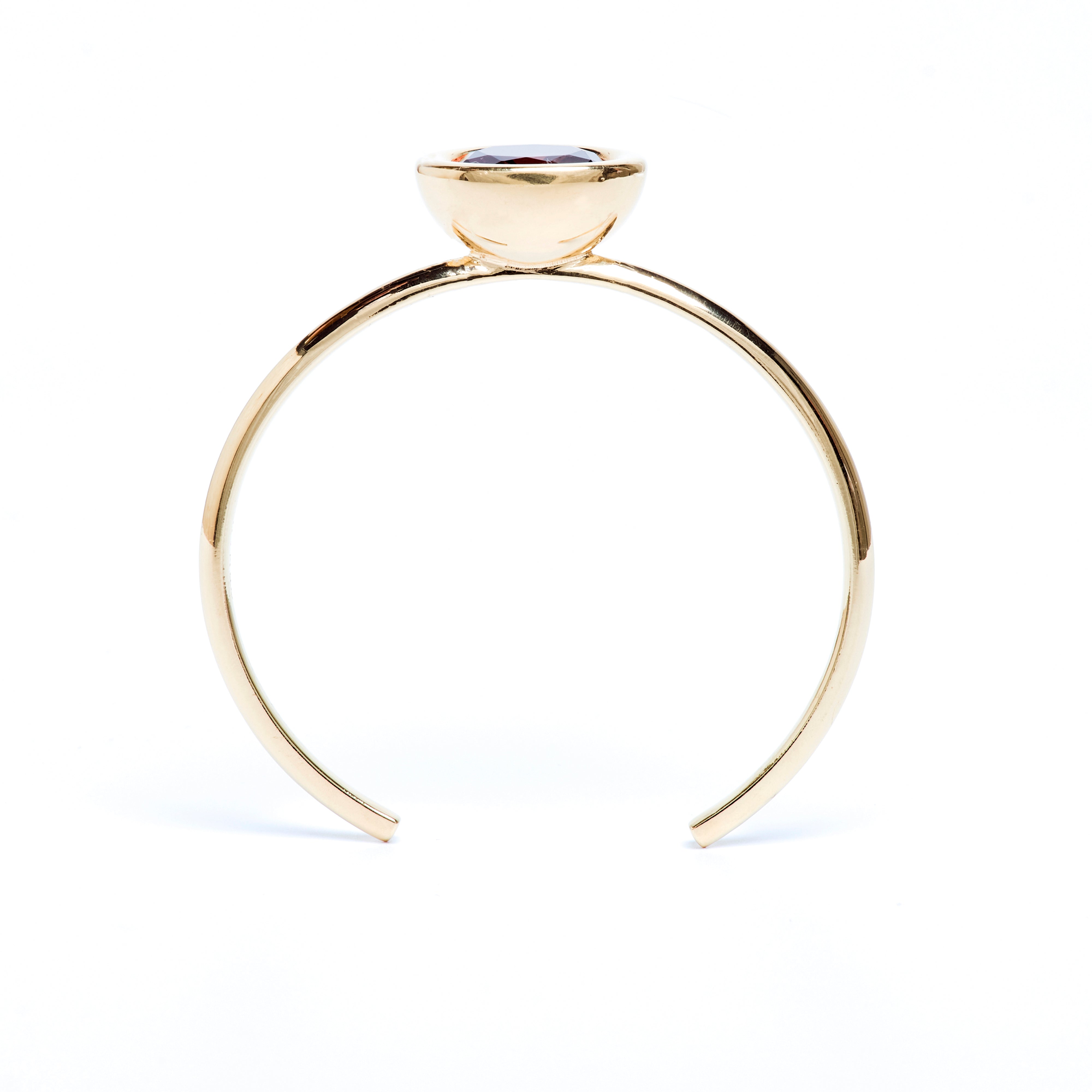 Gold ring with a central gemstone on a white background