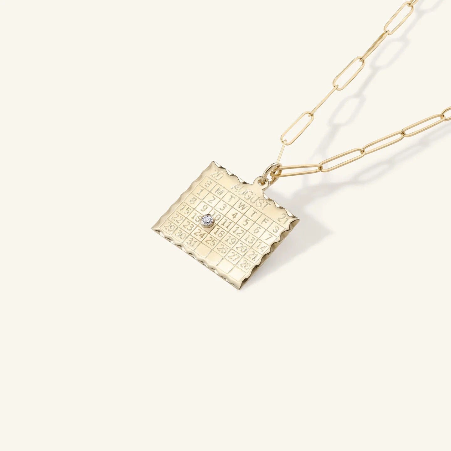 Gold necklace with a textured pendant on a white background