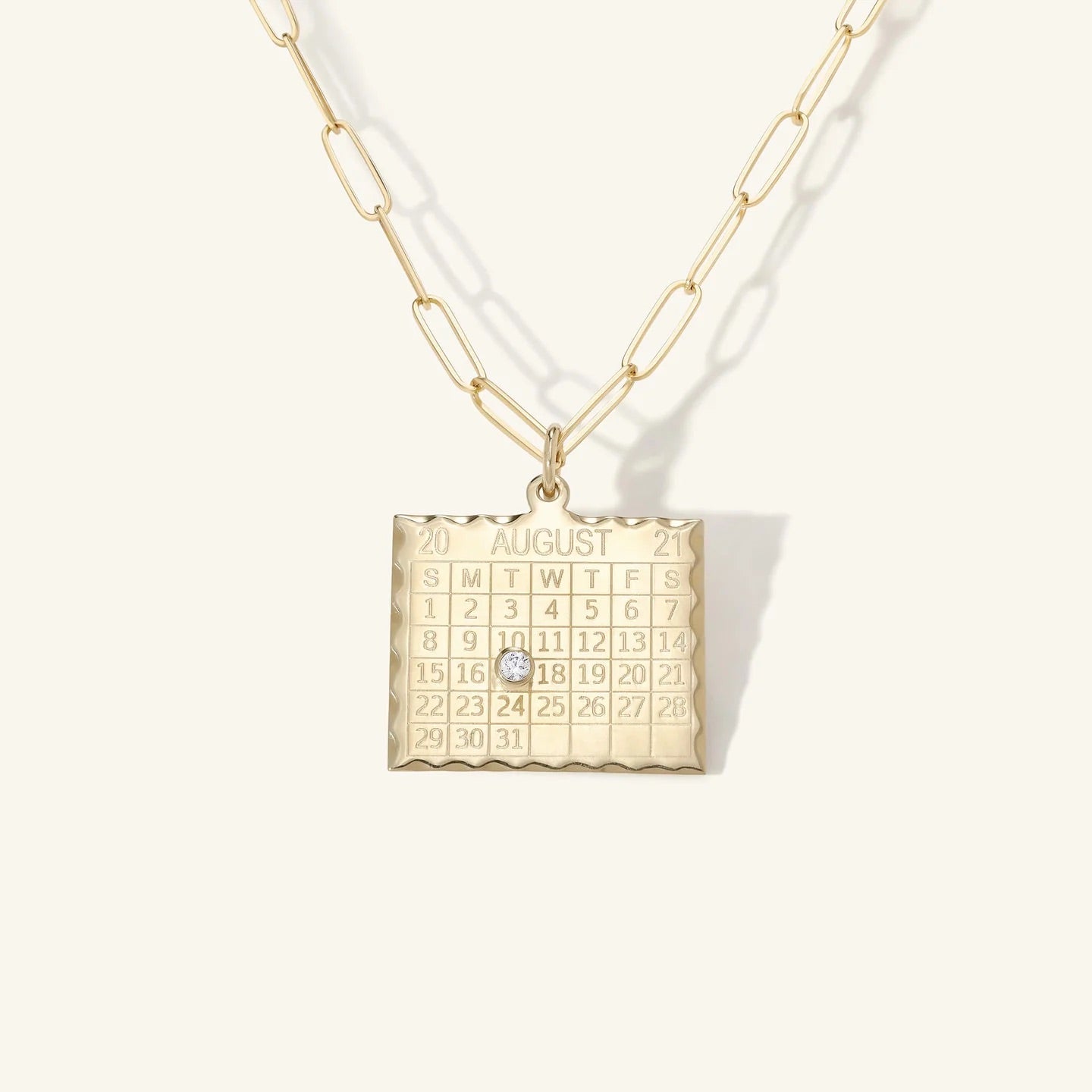 Gold necklace with a calendar pendant on a white background