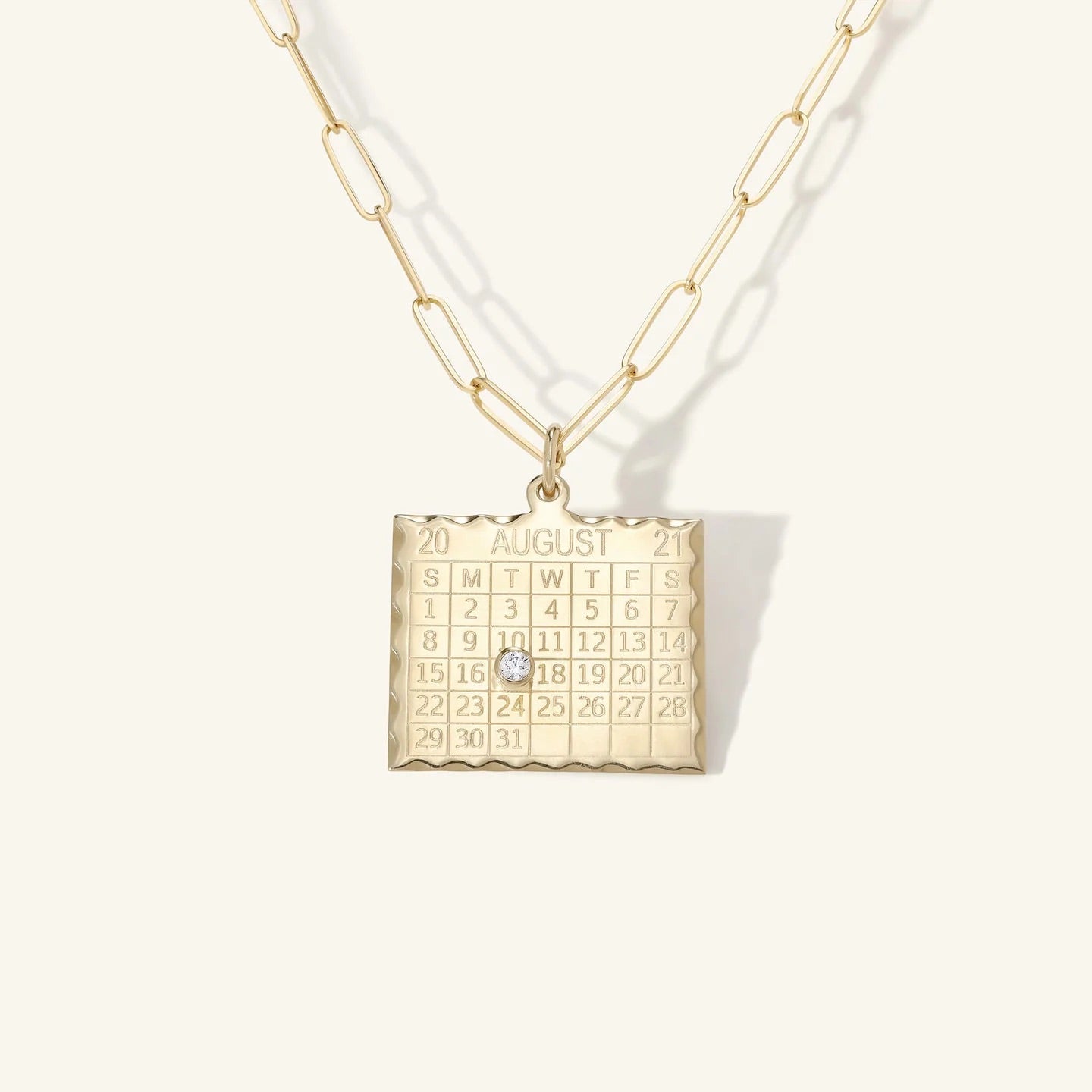 Gold necklace with a calendar pendant on a white background