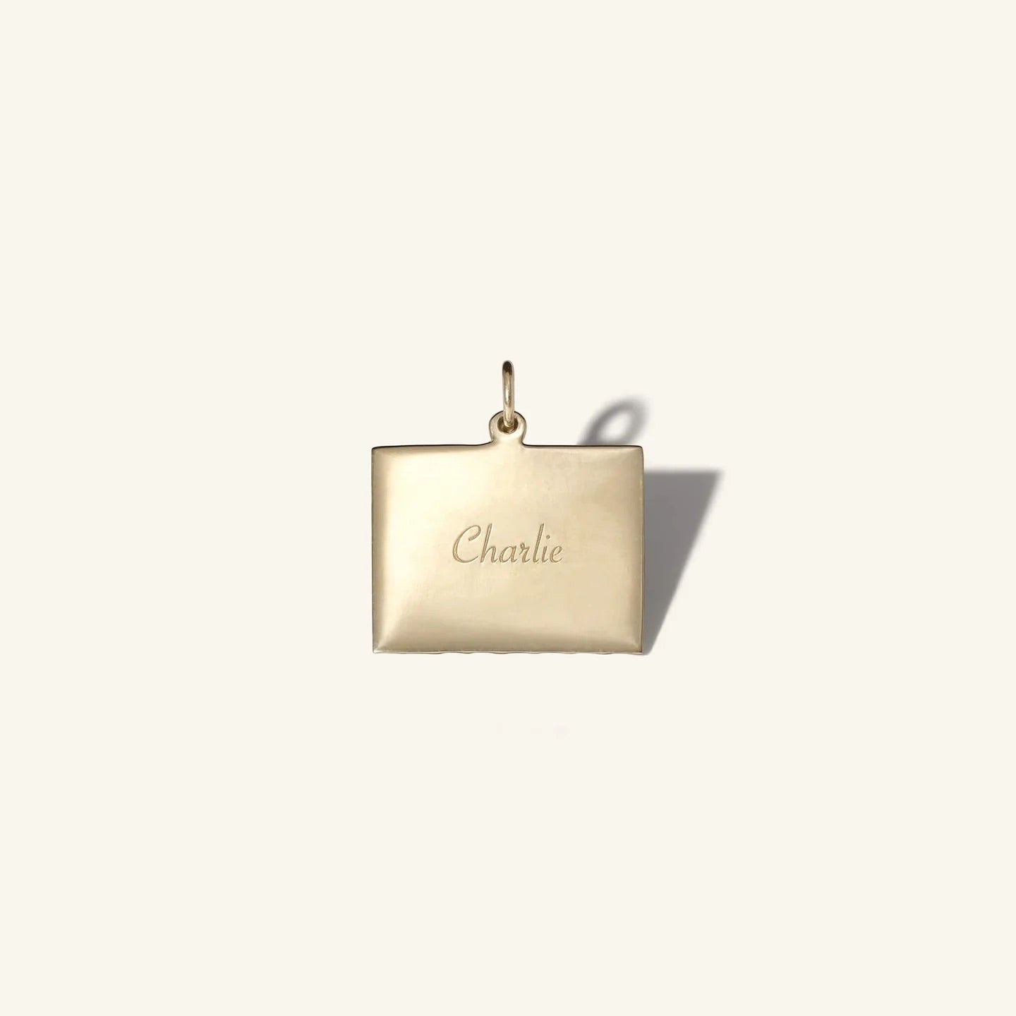 Gold pendant with 'Charlie' engraving on a white background