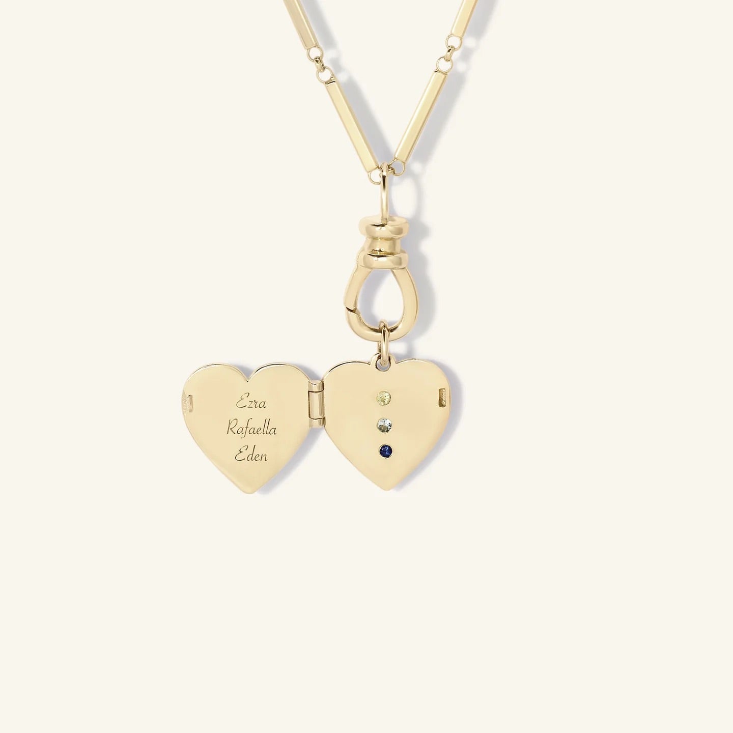Gold heart-shaped locket with engraved names on a white background