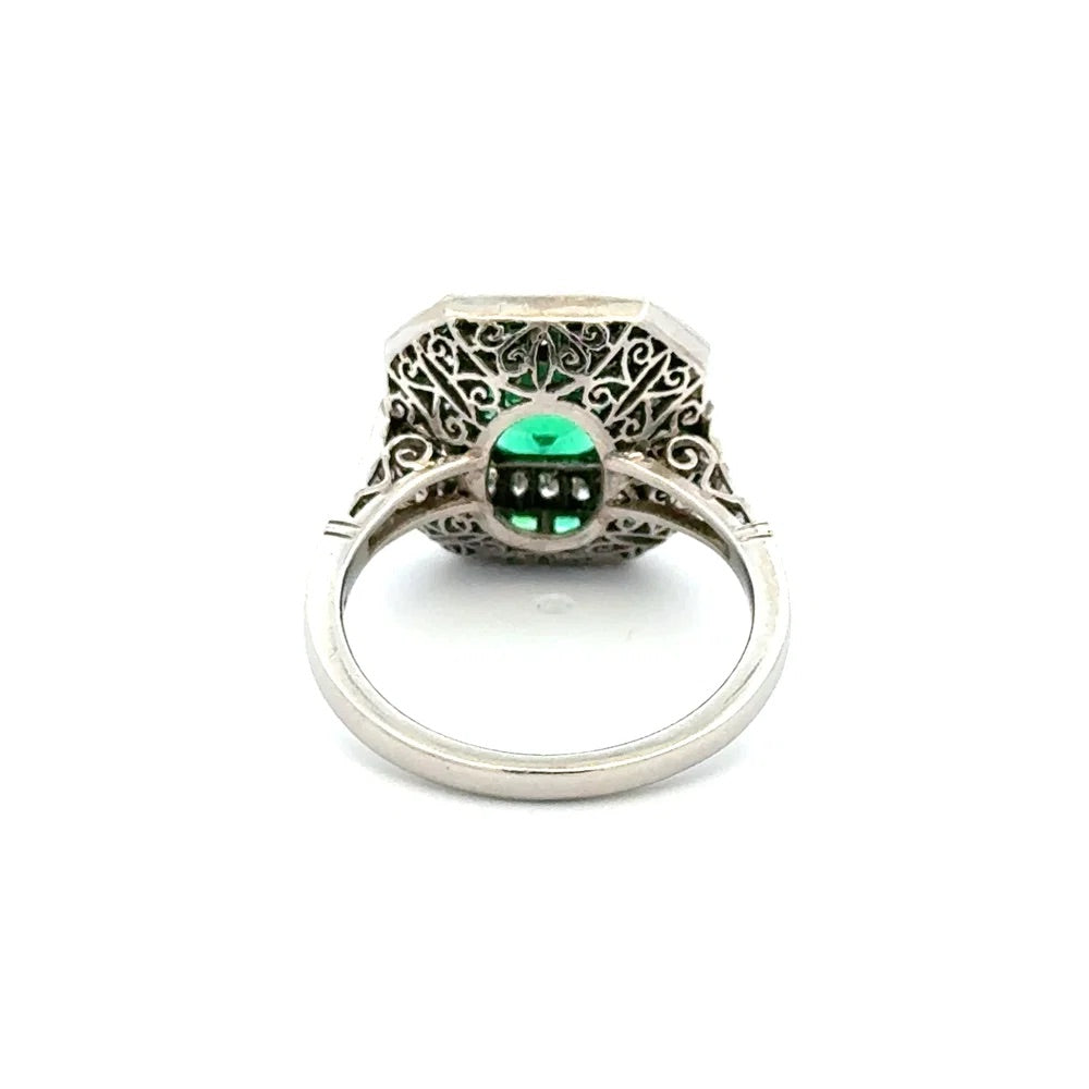 A silver filigree ring featuring a central green marquise-cut gemstone with three small clear accent stones below it, shown on a plain white background.