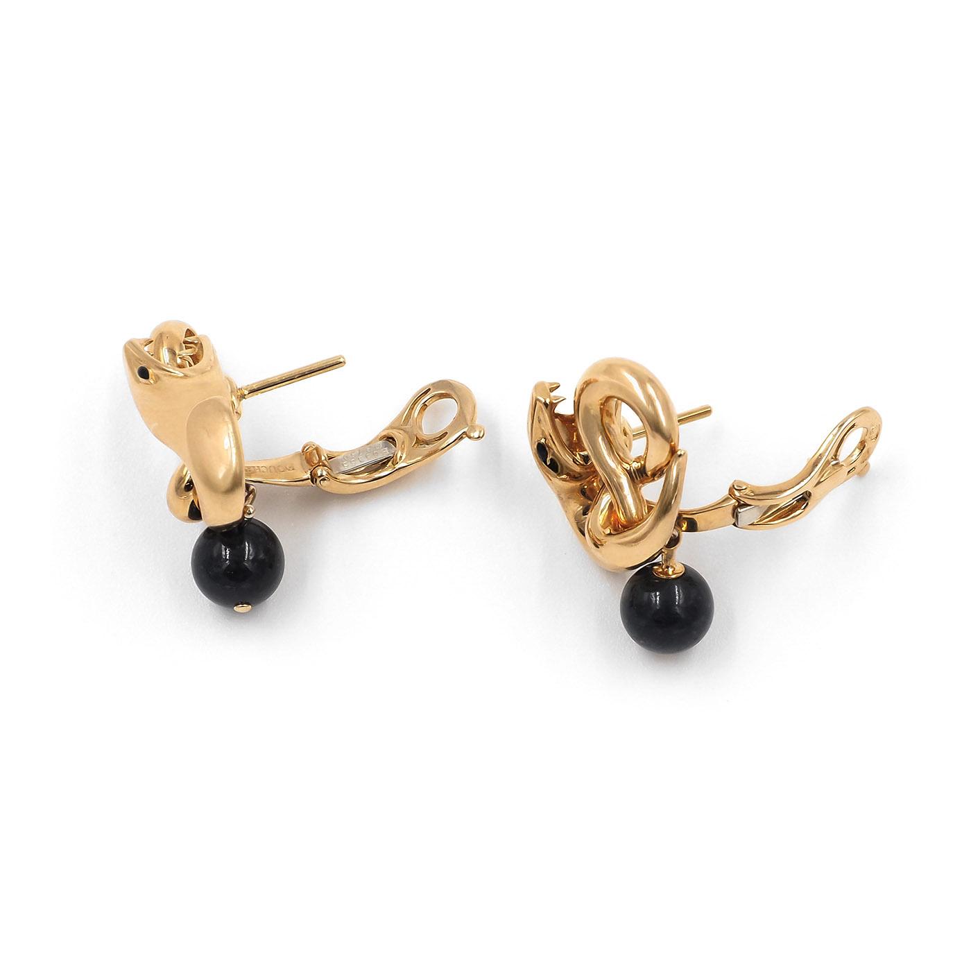Gold earrings with black beads on a white background