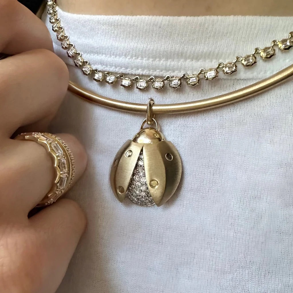 Gold bracelet with a detailed pendant on a white background