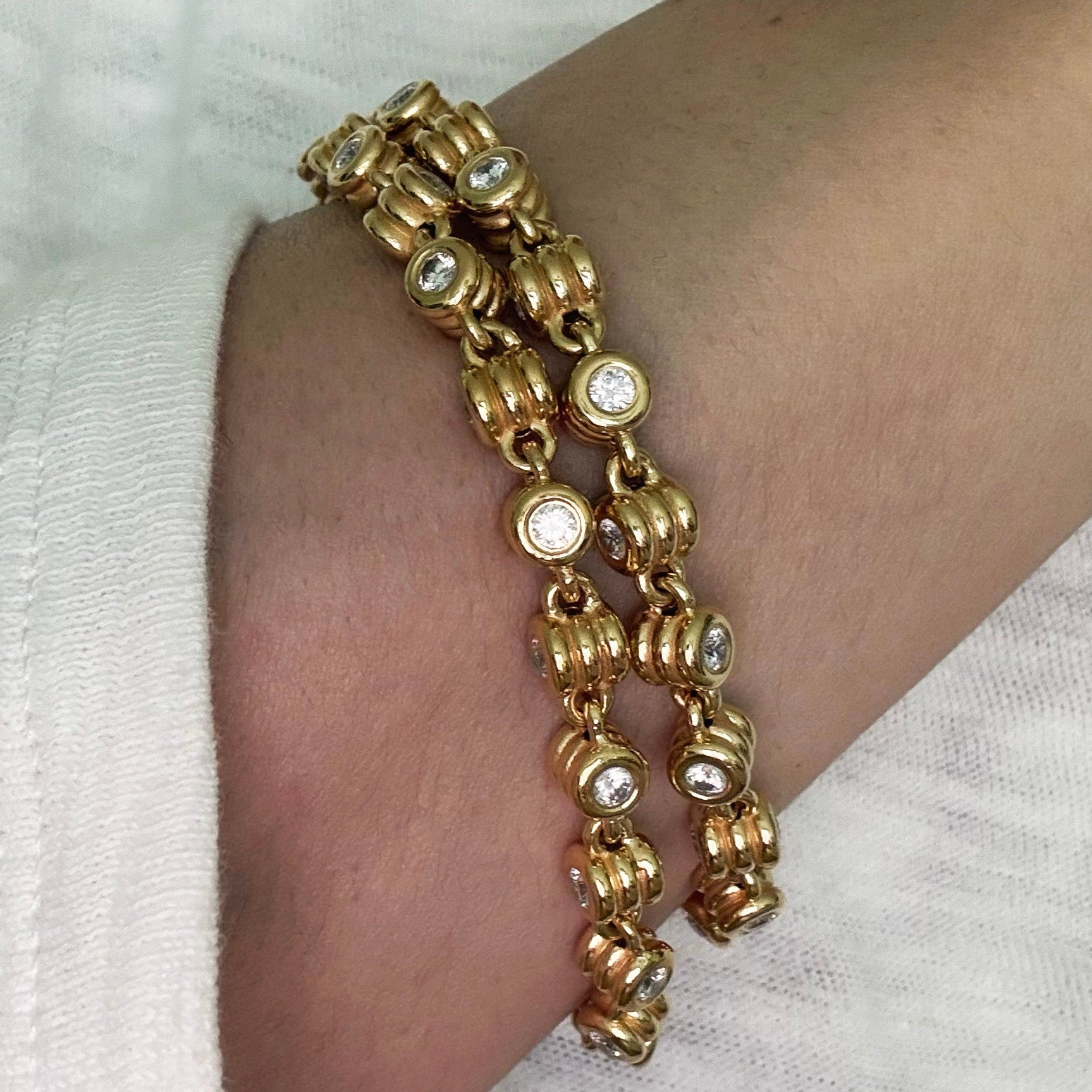 Gold bracelet with beads on a wrist against a white background