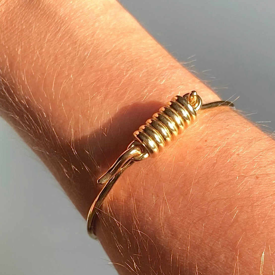 Gold bracelet on a wrist with a neutral background