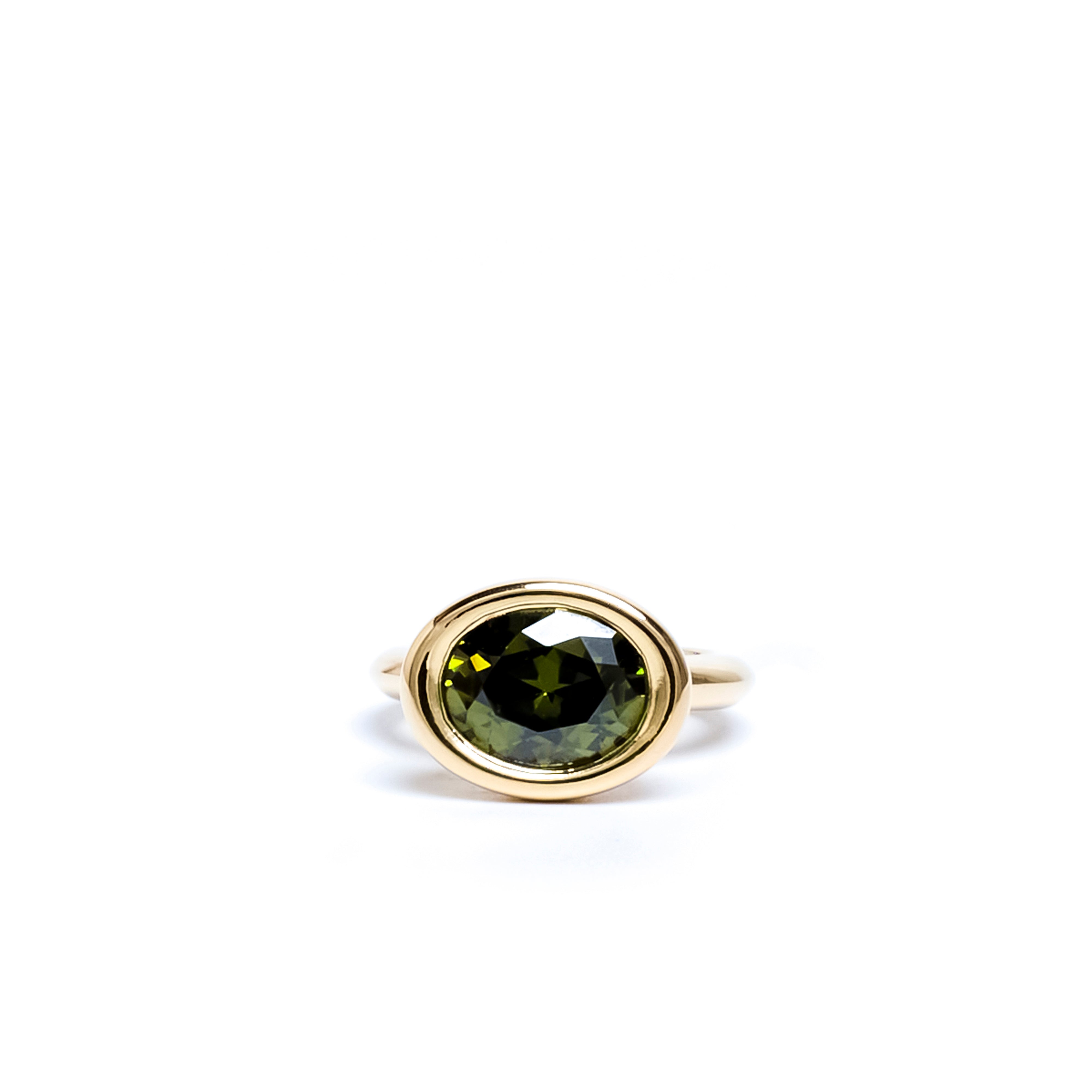 Gold ring with a green gemstone on a white background