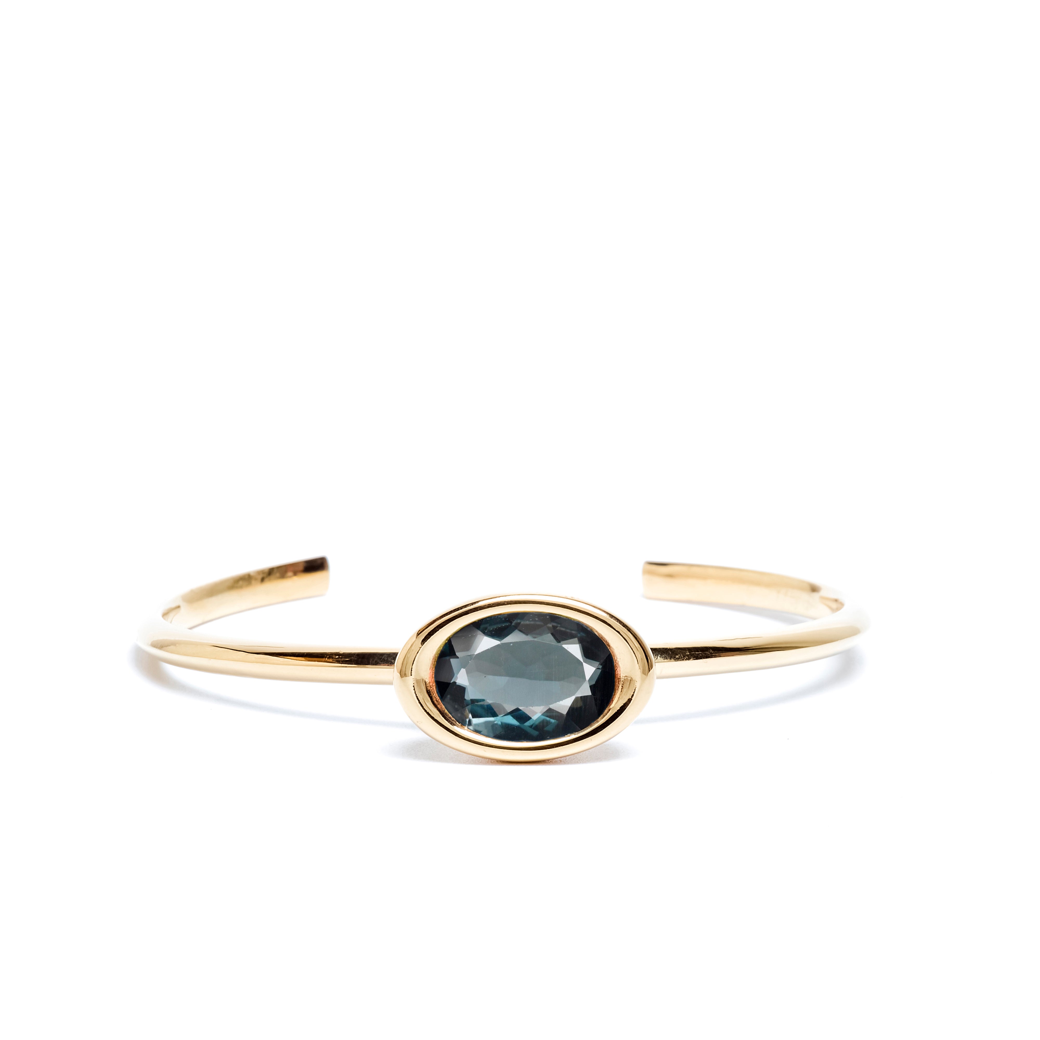 Gold bracelet with a central gemstone on a white background