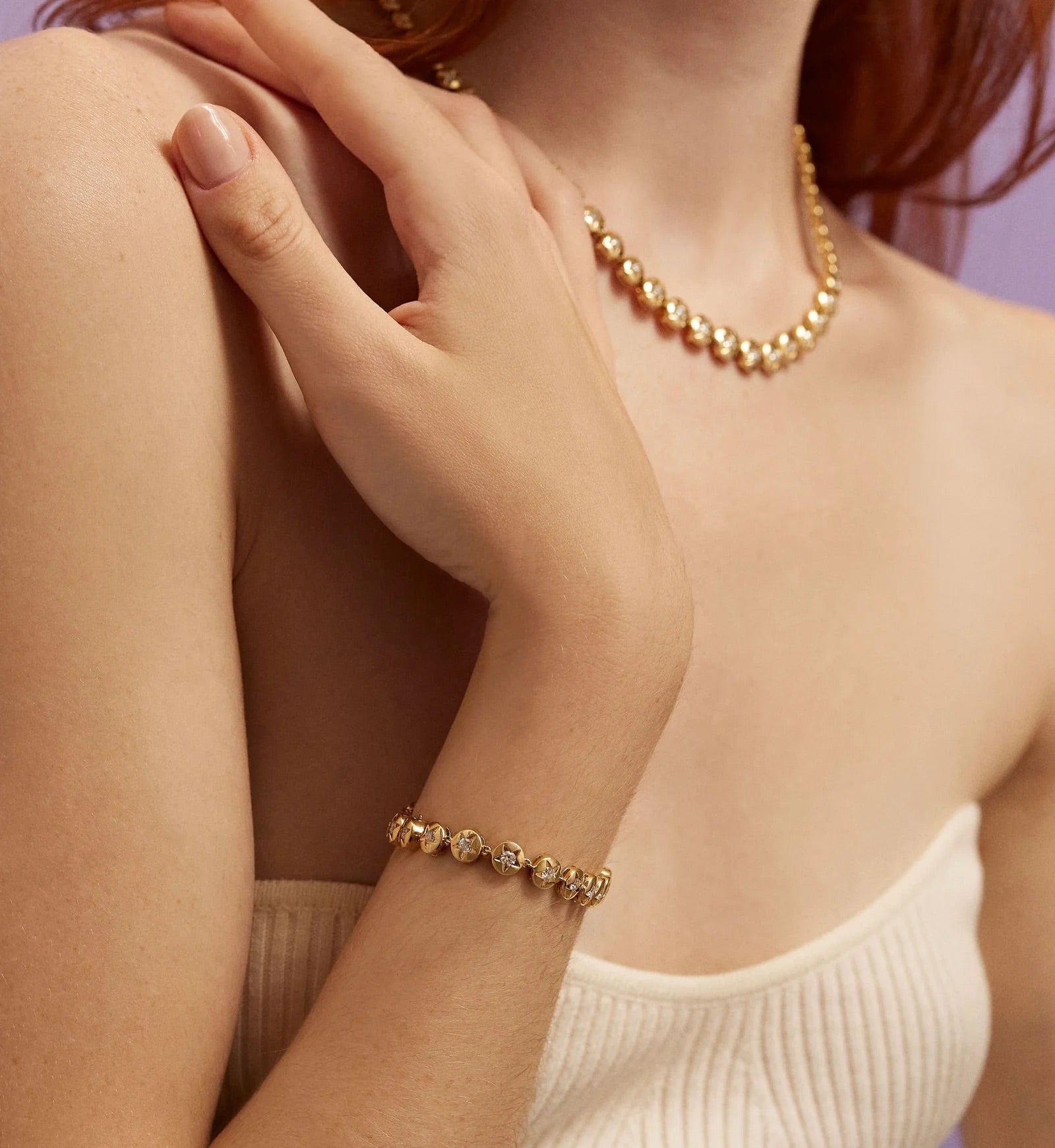 Gold bracelet and necklace on a person with a soft background