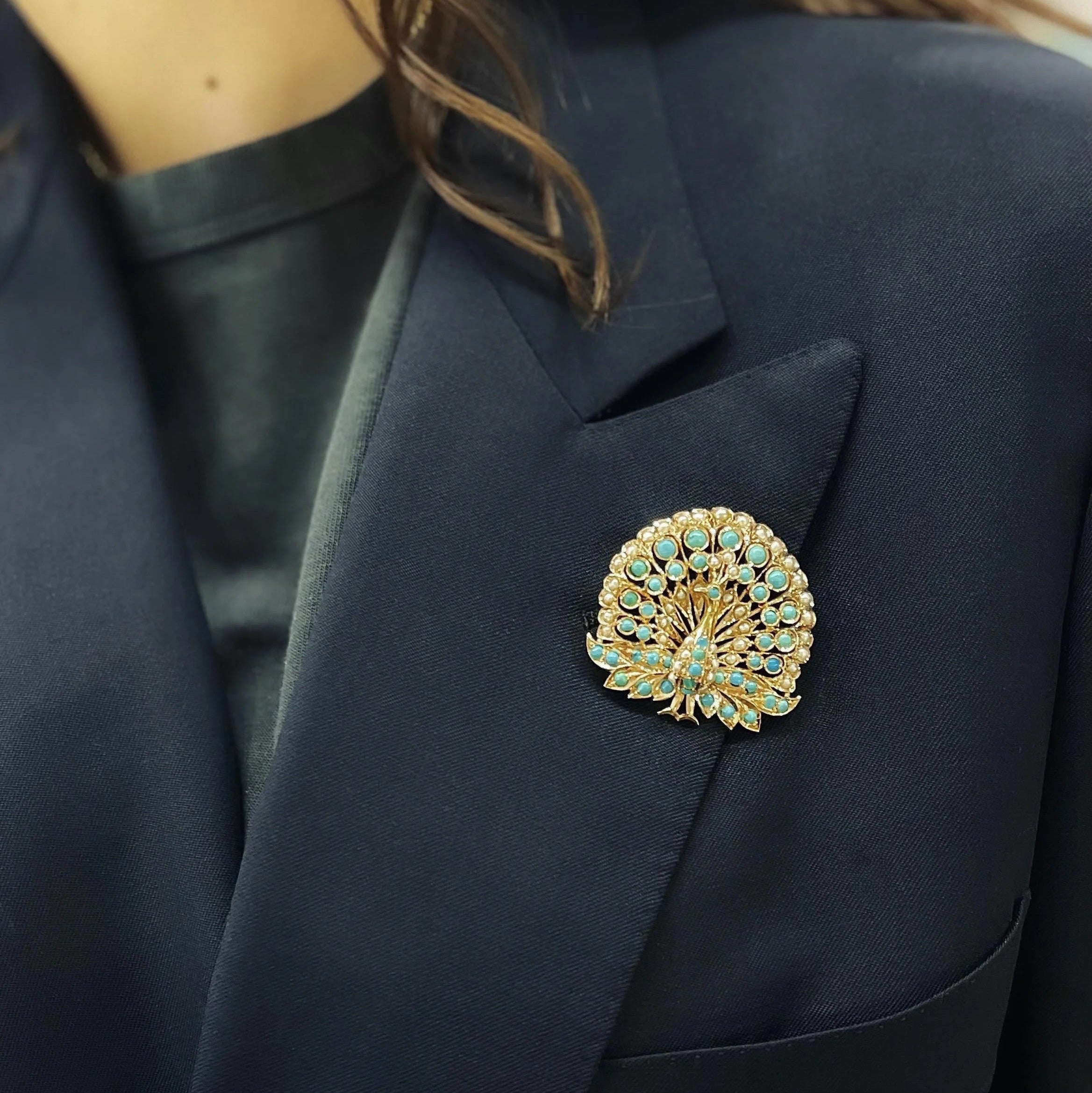 Navy blazer with a decorative brooch worn by a person