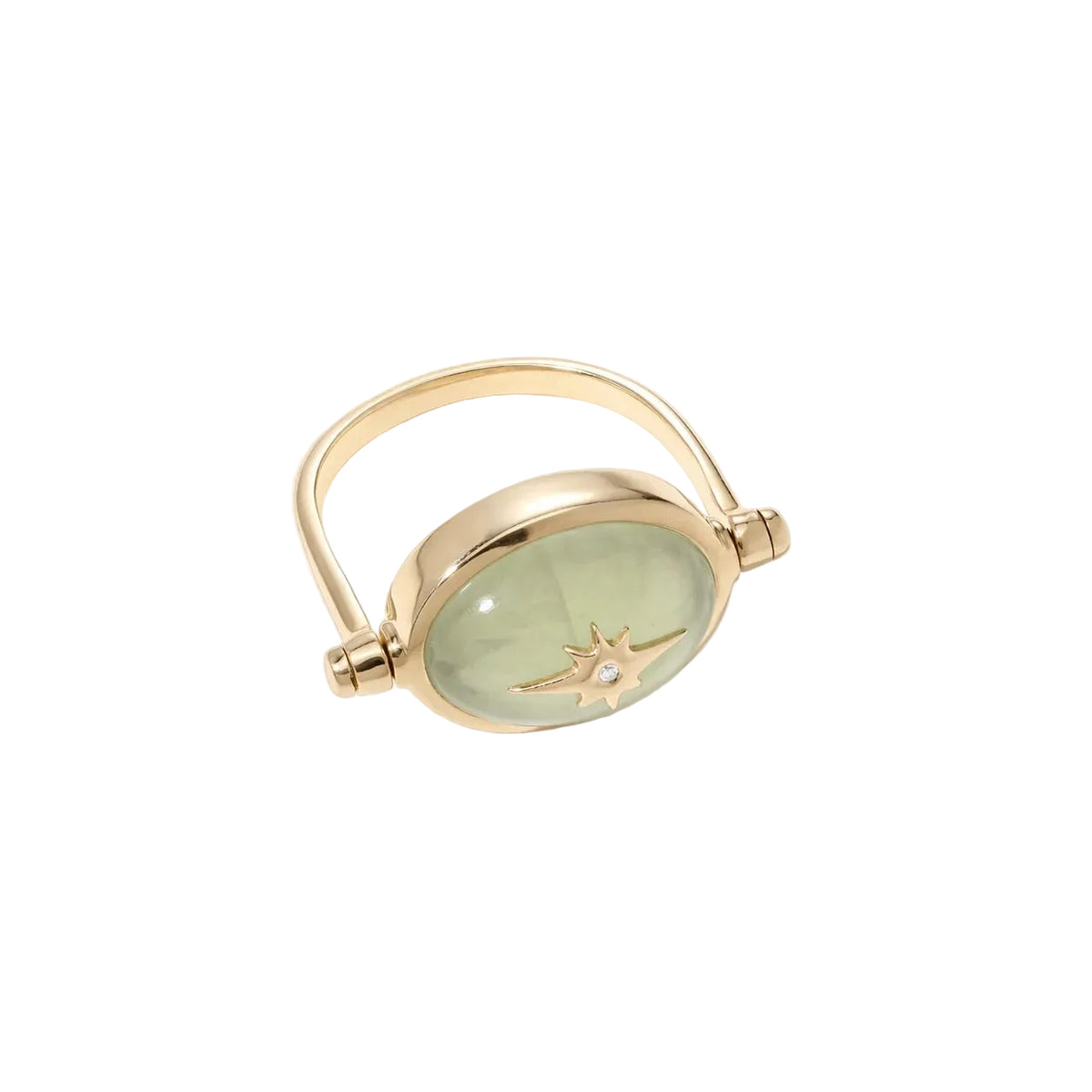 A gold ring featuring an oval light green cabochon stone with a gold compass star design in the center, set against a clean off-white background.