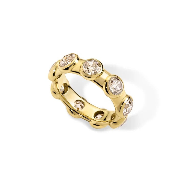 A yellow gold eternity-style ring featuring multiple bezel-set round clear gemstones, photographed on a clean white background.