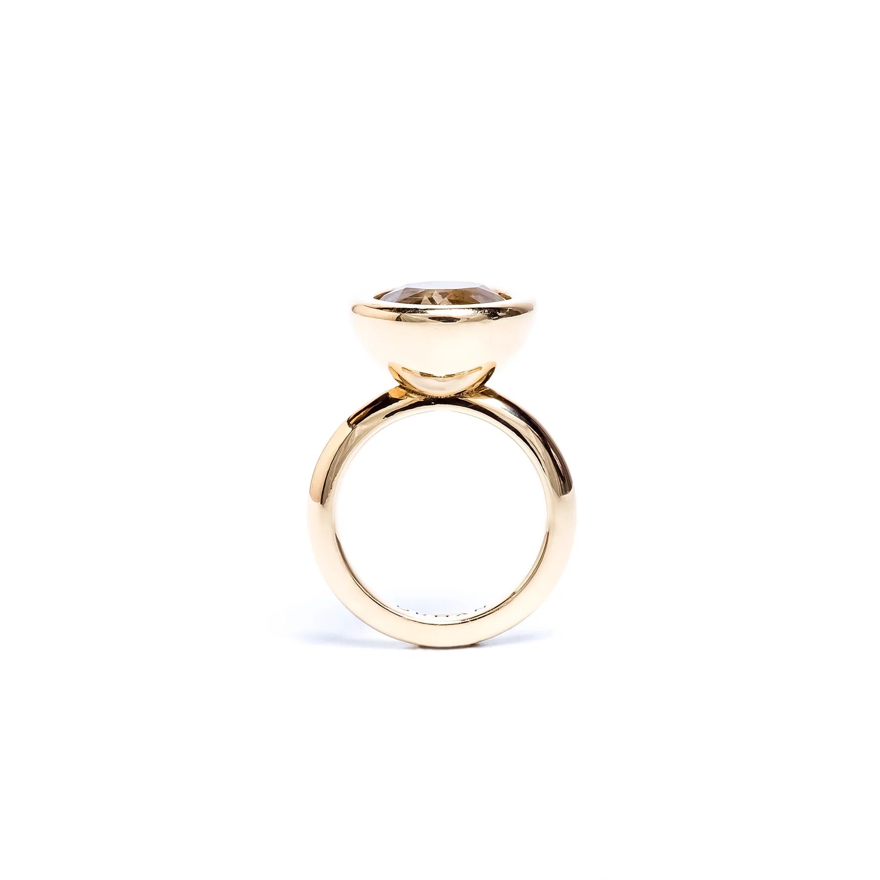 A gold ring with a bezel-set oval gemstone, shown from the side on a plain white background.