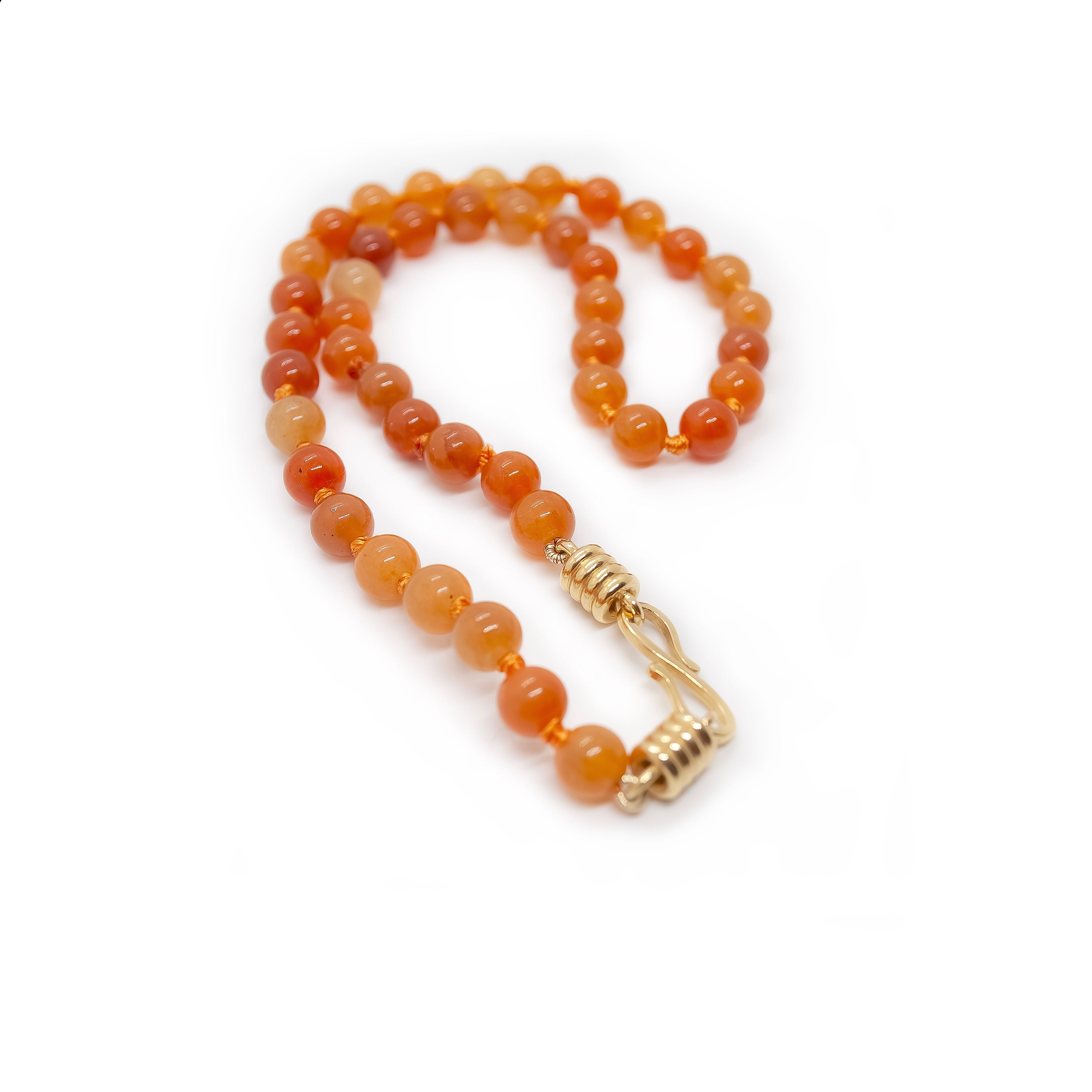 Necklace with orange beads and a gold clasp on a white background