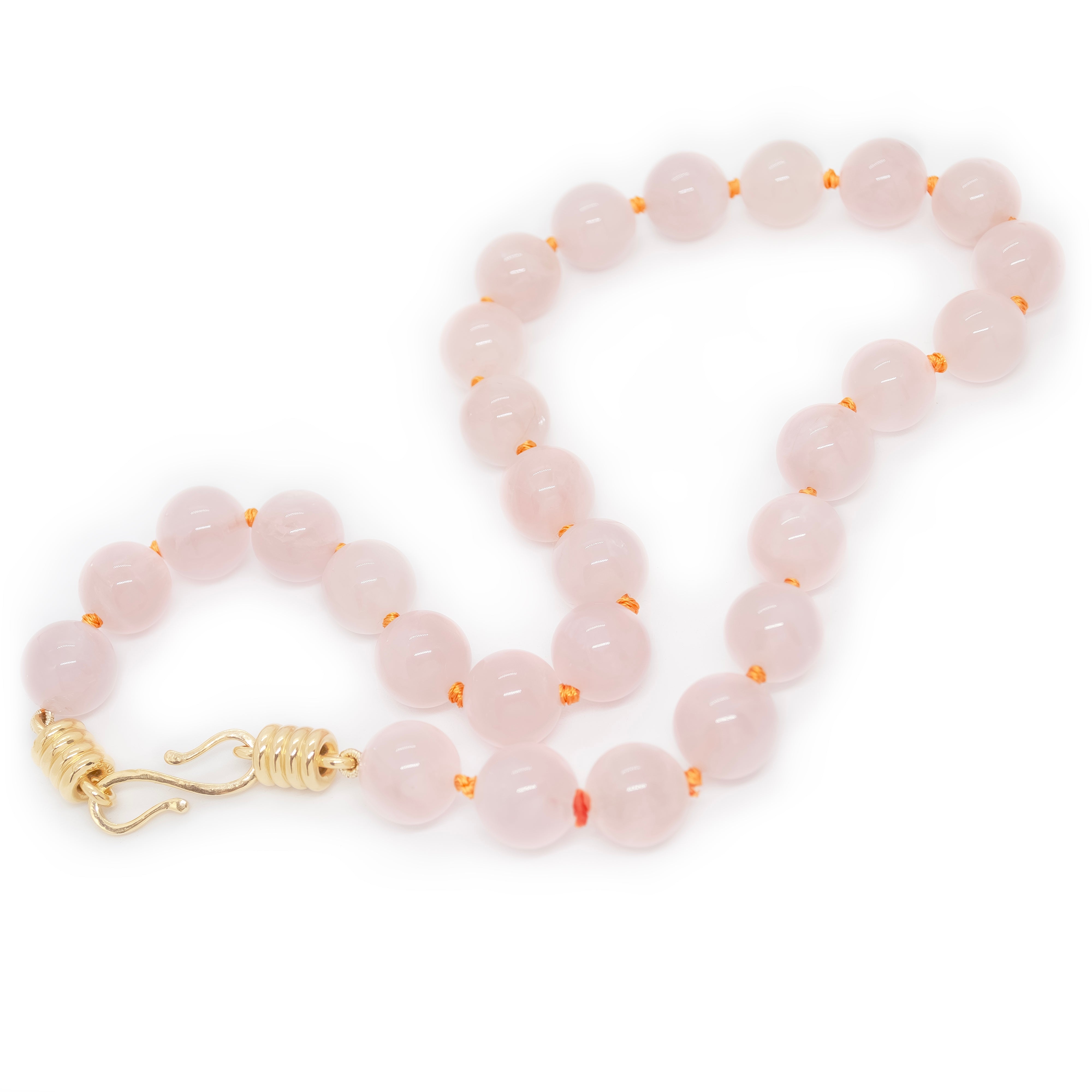 Rose quartz beaded necklace with gold clasp on a white background