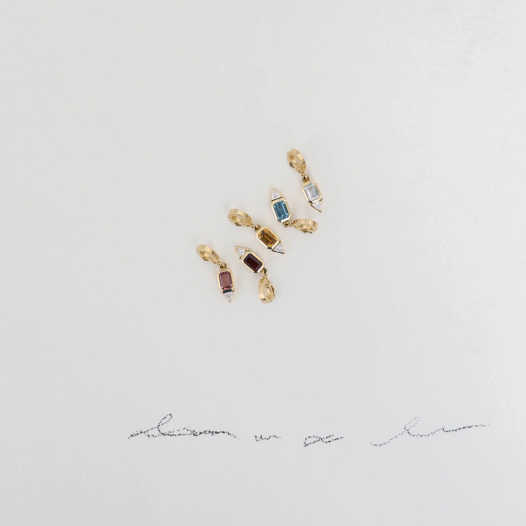 Pair of gold earrings with gemstones on a light gray background