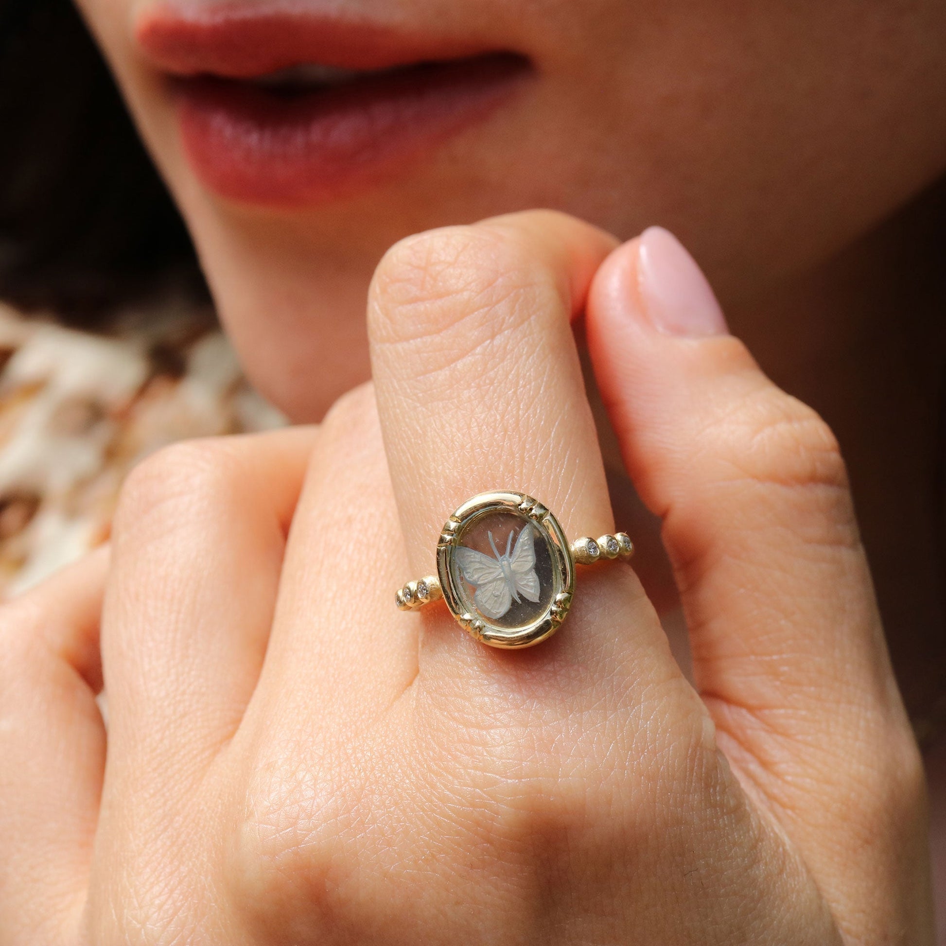 Close-up of a hand wearing a gold ring with a butterfly design.