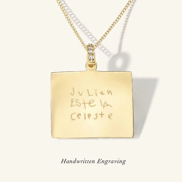 Gold pendant necklace with handwritten engraving on a white background