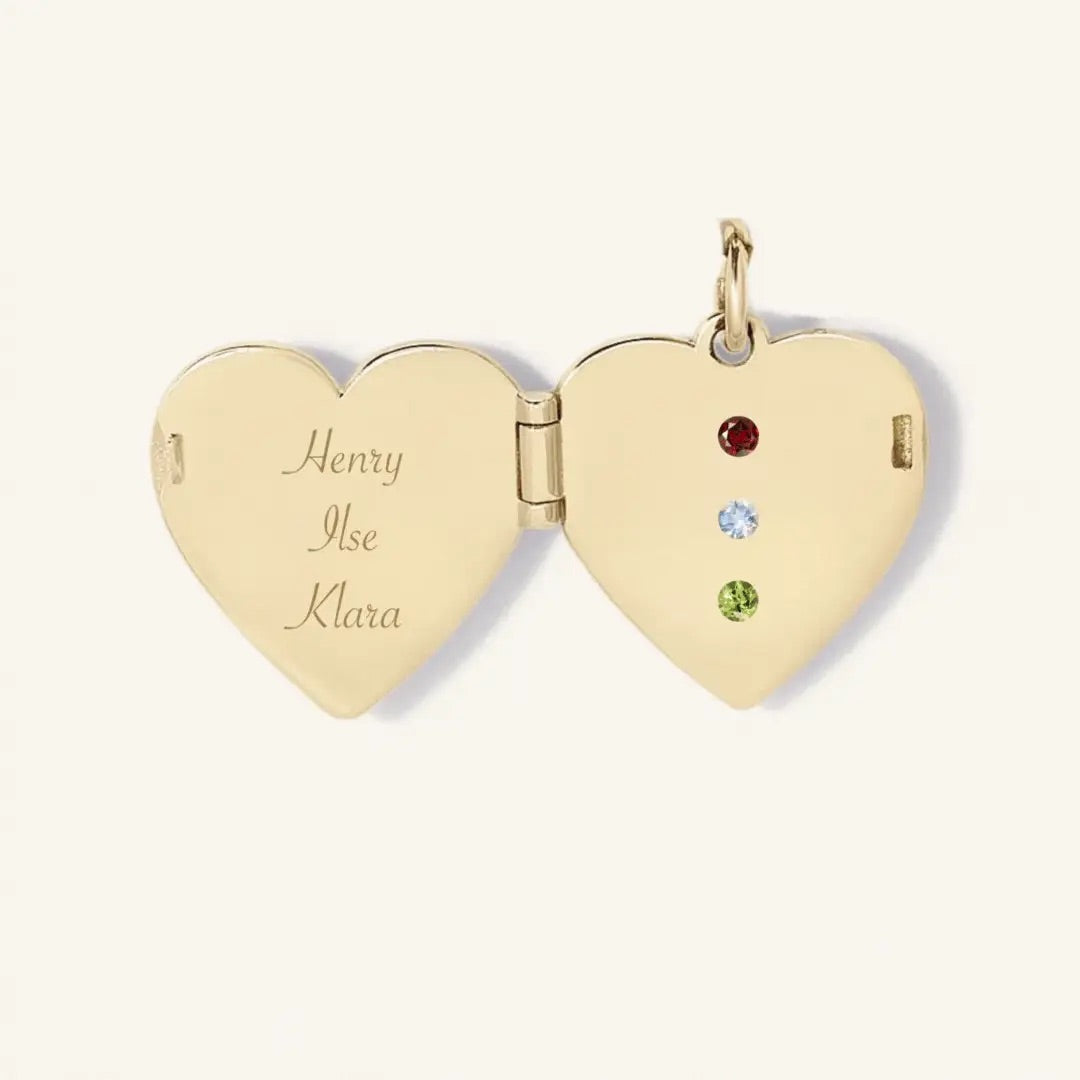 Gold heart-shaped locket with engraved names and embedded gemstones on a white background