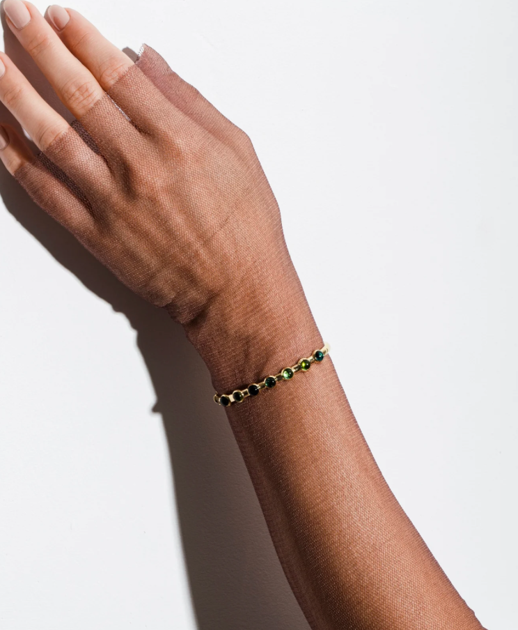 Hand wearing a bracelet on a plain background
