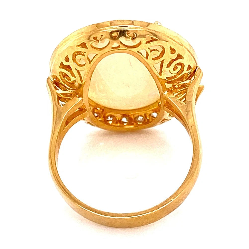 A yellow gold ring featuring a large oval bezel-set pale yellow stone with an ornate filigree-style top and small accent stones along the lower edge, shown on a white background.