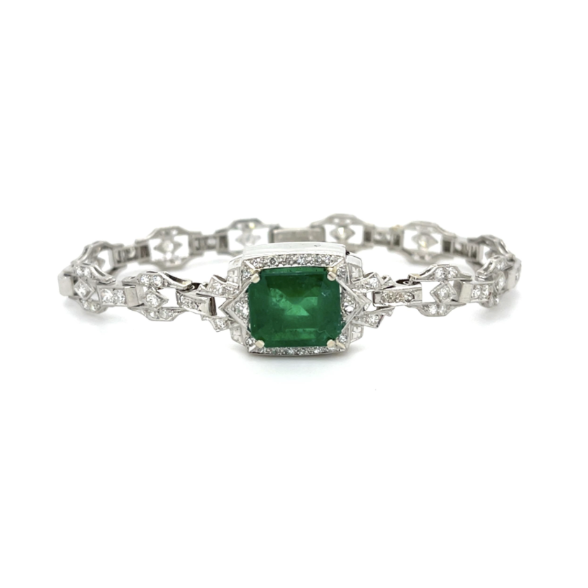 An Art Deco style silver-toned bracelet featuring a prominent rectangular emerald-cut green gemstone in a diamond halo, with an intricate openwork chain link design.
