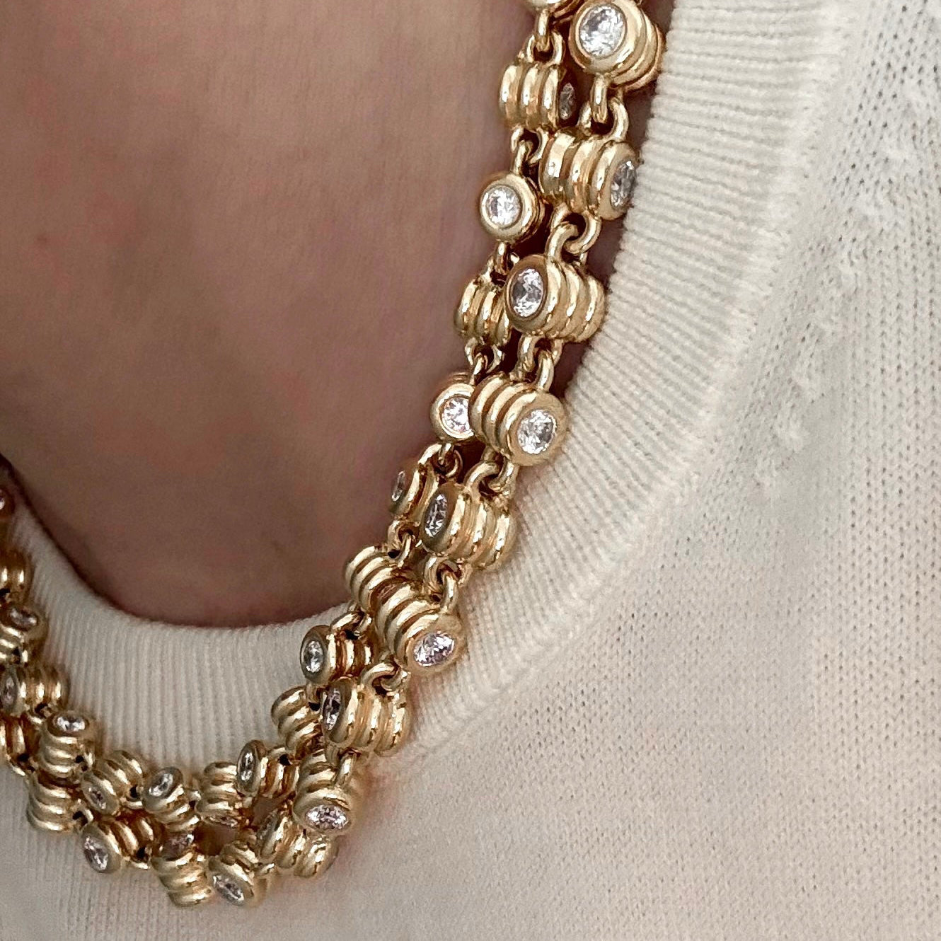 Gold necklace with embedded diamonds on a neutral background