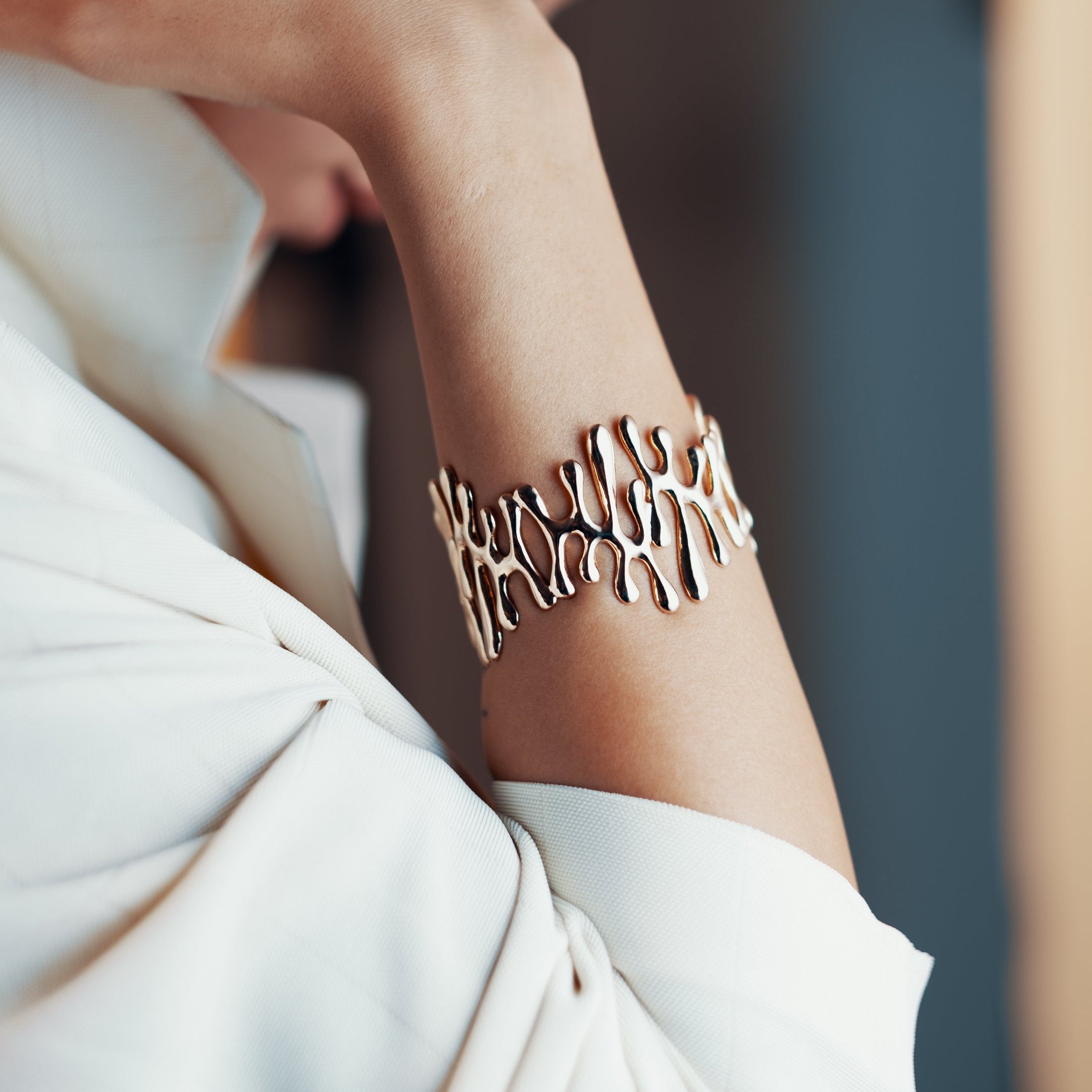 Person wearing a gold bracelet with a blurred background