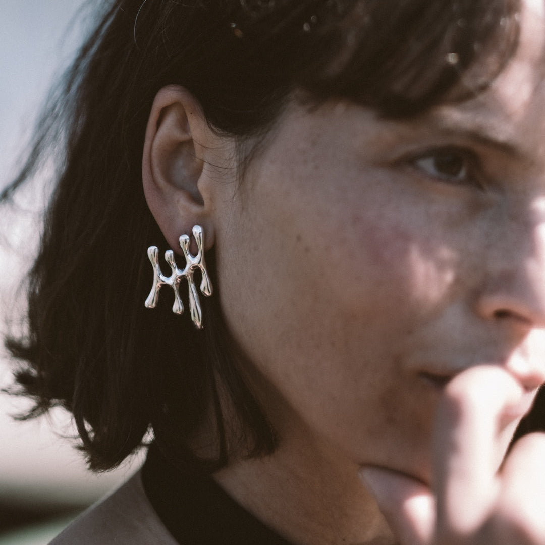 Close-up of a person wearing silver earrings with a blurred background
