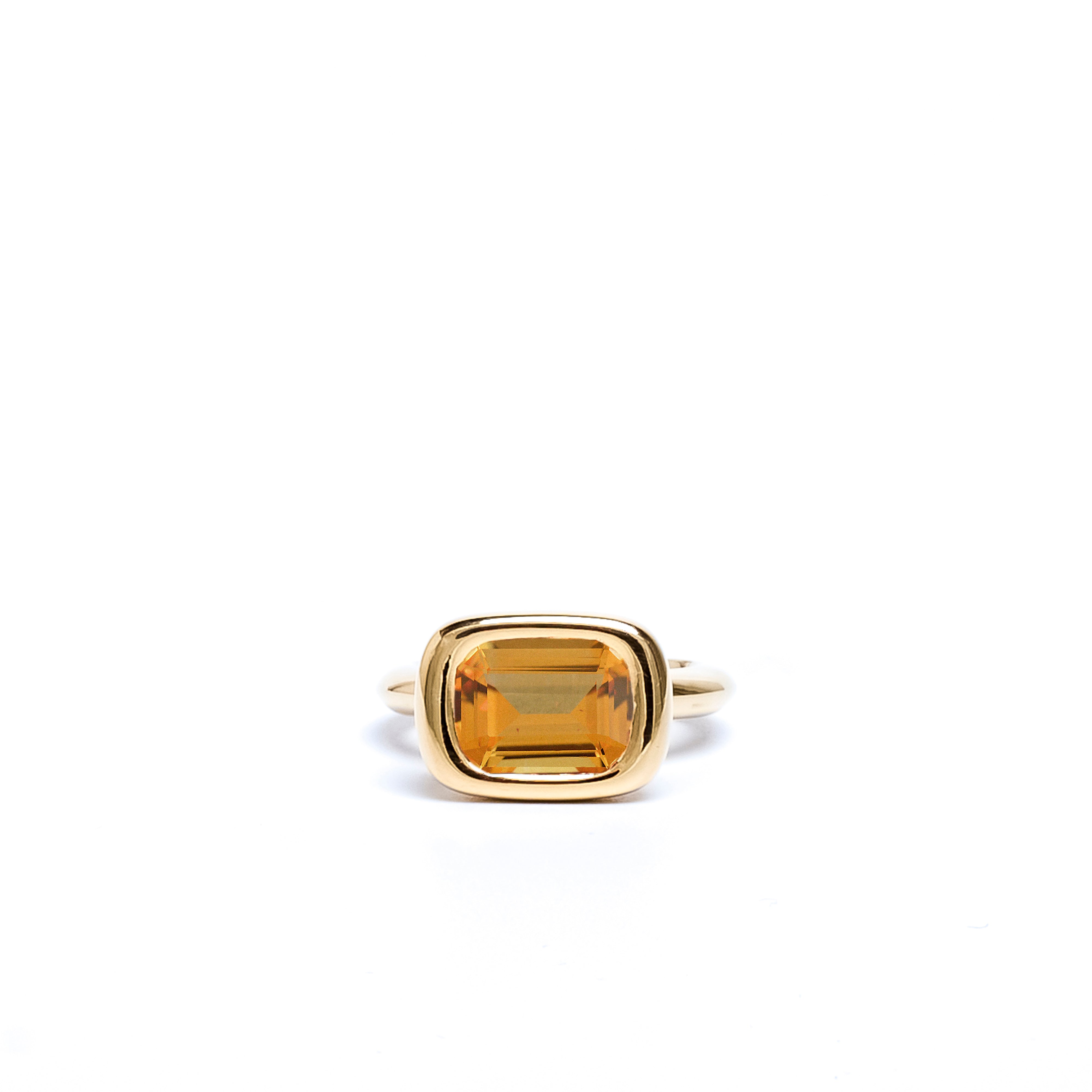 Gold ring with a rectangular citrine stone on a white background