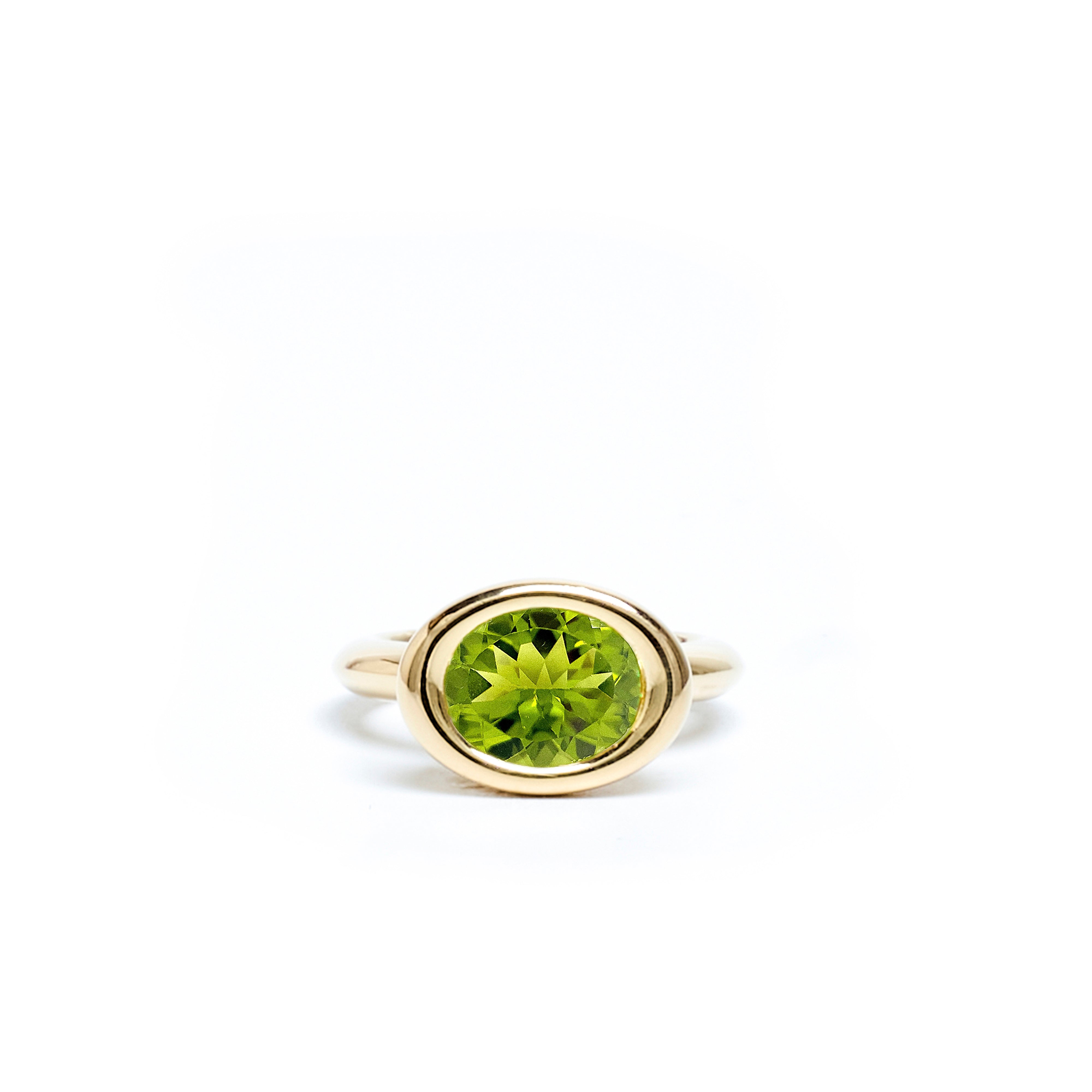 Gold ring with a green gemstone on a white background