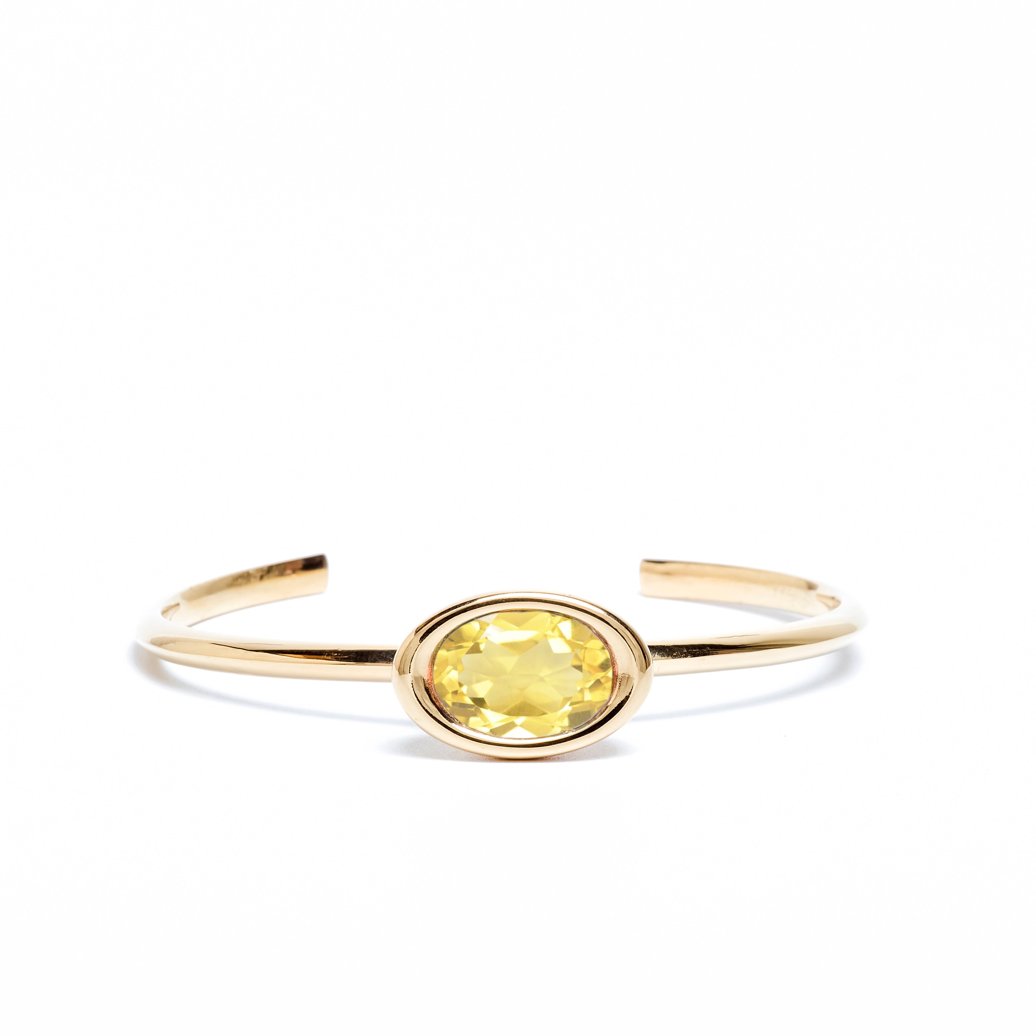 Gold bracelet with a yellow gemstone on a white background